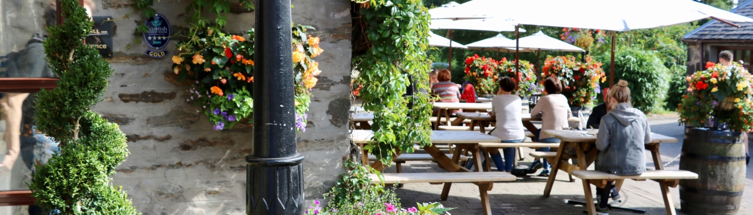 The Old Mill Inn in Pitlochry in the summer sunshine with people enjoying food and drinks at the outdoor tables