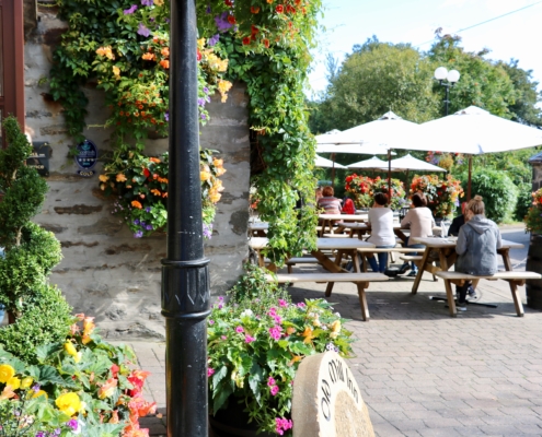 The Old Mill Inn in Pitlochry in the summer sunshine with people enjoying food and drinks at the outdoor tables